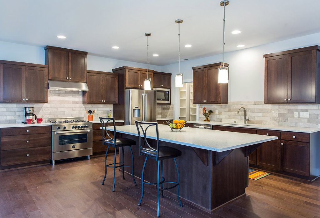 Kitchen with kitchen island, gas range, quartz counters, pendant lighting, custom cabinets.